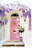 This photograph shows a peaceful new-home doorway in Shooter's Hill, styled with the softness and charm of a thoughtful housewarming surprise. The focal point is a pale blush-pink front door, its surface gently reflective, set within smooth, sunlit white walls that give the entrance a bright, open feel similar to the calm residential streets around Oxleas Woods. Above the door, lavish tendrils of wisteria tumble down, dripping with clusters of lavender blossoms that look almost cloudlike, hinting at a sweet, powdery fragrance drifting through the air. At the base of the doorway, resting neatly on the step, stands a simple grey metal bucket, transformed into something special by the bouquet it holds. Inside, a generous gathering of white and cream roses nestles together, each bloom plush and velvety, layered with petals that curl softly at the edges. Wisps of fresh green foliage thread between the roses, adding depth and a gentle, garden-fresh contrast. A soft pink ribbon is tied around the bucket, its satin loop and flowing tails echoing the tone of the front door and adding a graceful finishing touch. Sunlight filters from one side, creating delicate shadows across the steps and enhancing the pastel harmony of pinks, whites, and greens. The whole scene feels like a quiet celebration of moving in: a floral welcome arranged with care by a local Shooter's Hill florist, perfect for marking the start of a new chapter with beauty, calm, and the comforting message that this place is truly home.